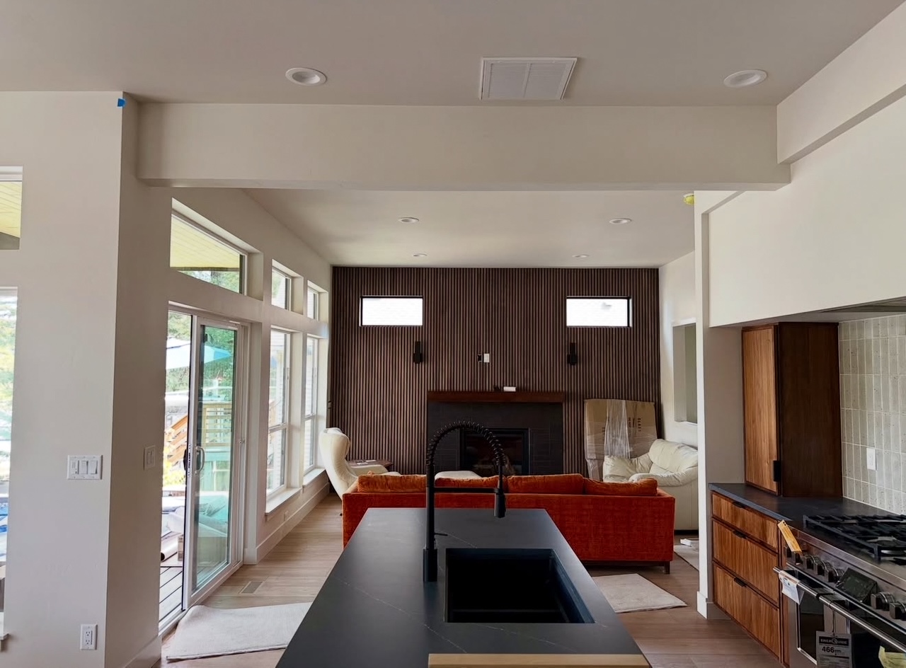 Open-concept living room and kitchen with island sink, orange couch, fireplace, and wood slat accent wall.