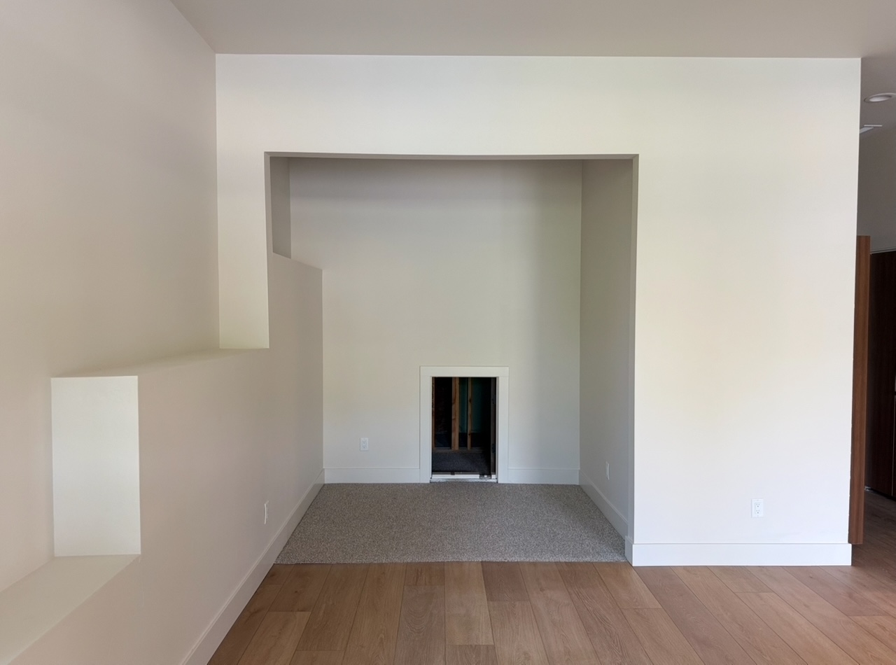 Recessed painted drywall alcove with wood flooring, carpeted section, and low rectangular access opening.