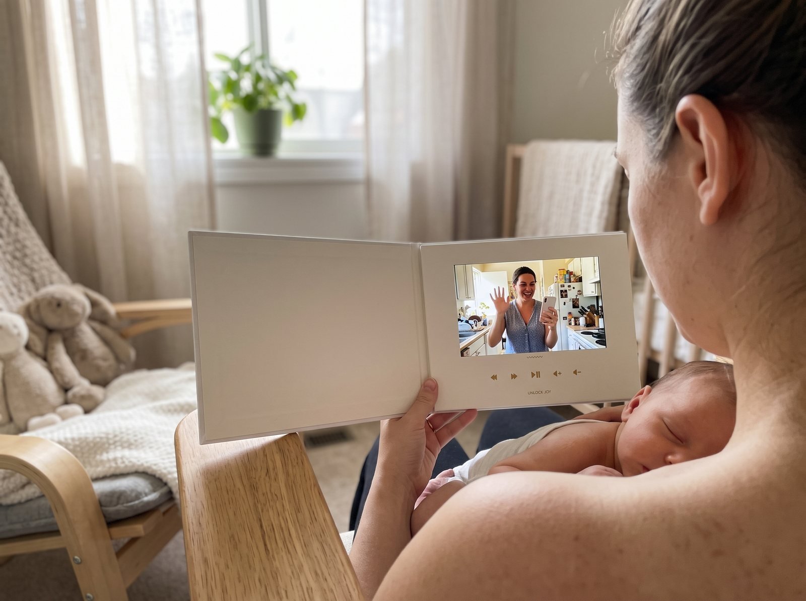 New mom watching a group video on a Tribute Video Book while her baby sleeps